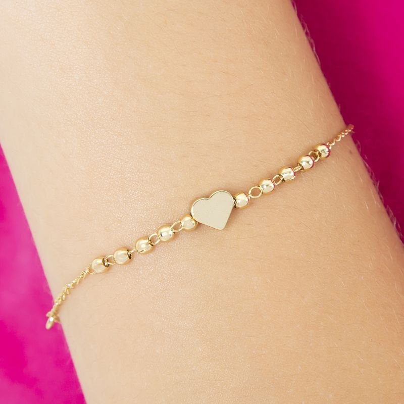 PULSEIRA INFANTIL DE BOLINHAS E UM CORAÇÃO DOURADO NO CENTRO